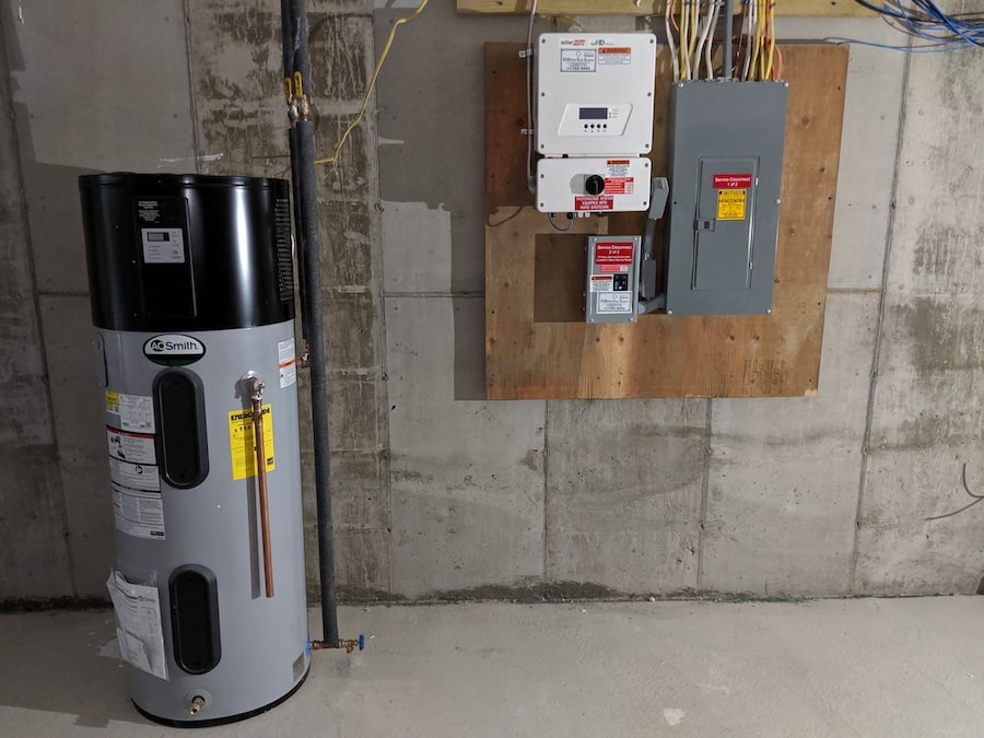 A heat pump water heater is housed in the basement next to solar photovoltaic (PV) equipment. 