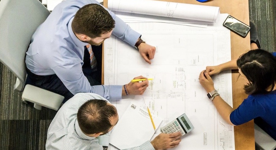 Builder and trades at table reviewing house plans 