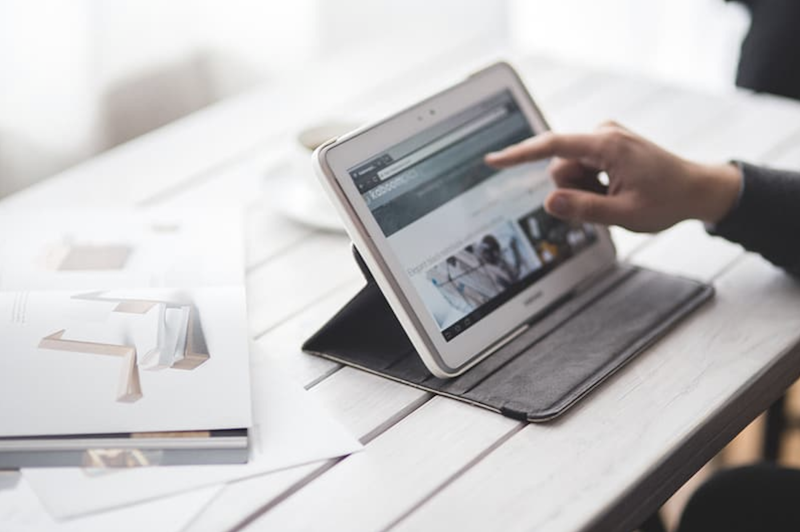 person sitting at table using a tablet to view a website