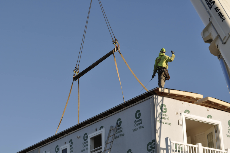 prefabricated roof panel being lowered into place on site by crane