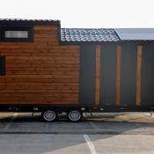 A newly built tiny home sits on trailer in a parking lot ready to be moved to its home