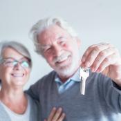 close up of mature man and woman holding a key of a new home