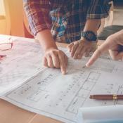 Two home builders look over plans on table