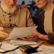 An older couple sits at a table, looking over budget