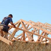 A builder works on the roof of a house.