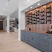 A display case of wine hangs over gray cabinetry in a modern home.