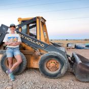 Lisa Morey, founder of Nova Terra, stands in front of machinery at a project site.