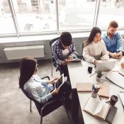 A group of Gen Z coworkers sit around a table working together