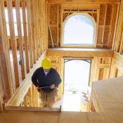 A contractor walks up the stairs in a partially constructed home