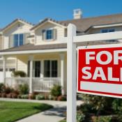 A home with a red "For Sale" sign in the front yard