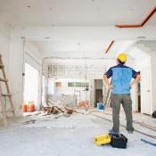 A man in a yellow hard hat looks over home renovation work 