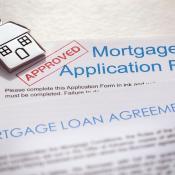 A mortgage loan application with a stamp of approval and a set of house keys sitting on top of it