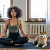 Woman doing yoga with dog in home room