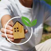 Hand holding model of house to show net-zero goal for homes