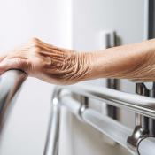 Elderly woman grabbing handrail in bathroom