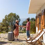 Homeowner greeting guest with suitcase outside of vacation rental 