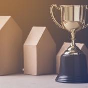 Golden trophy next to small wooden houses