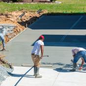 Workers spreading concrete on construction site