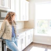 Female homebuyer standing in modern kitchen looking out window