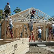 Construction crew framing new house with timber