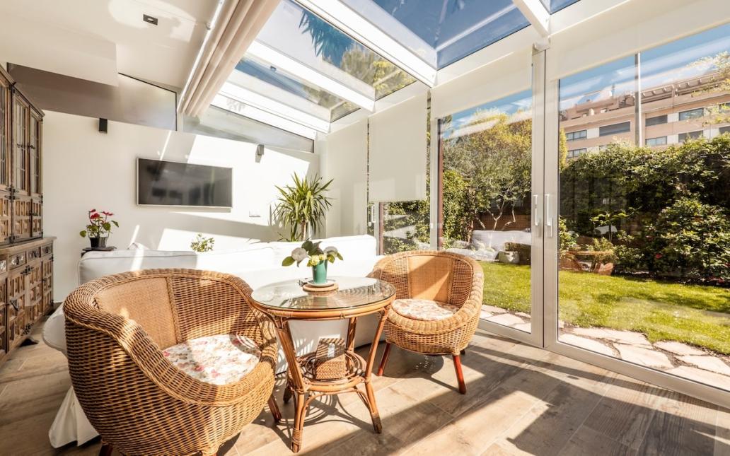 Sun room with large skylights and screen door looking out onto a landscaped backyard