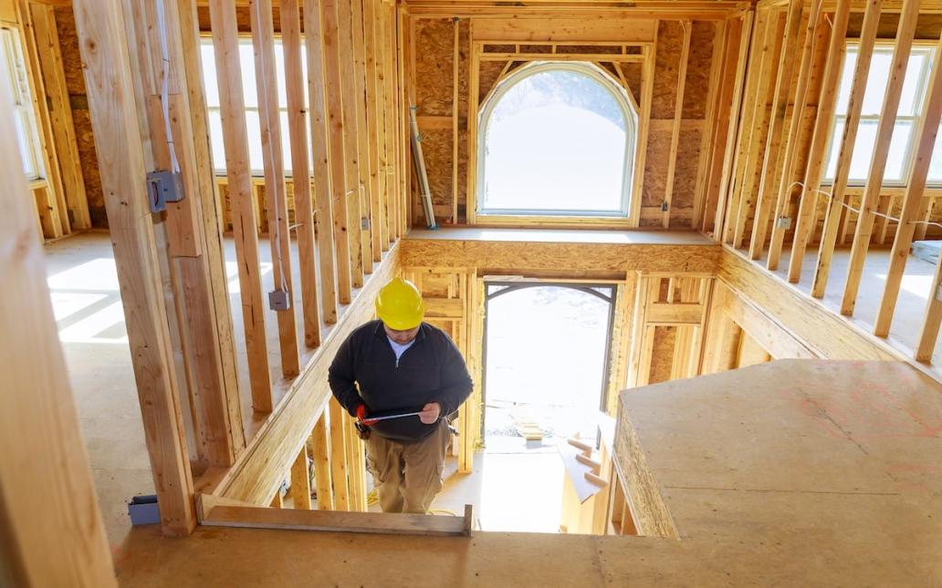 A contractor walks up the stairs in a partially constructed home