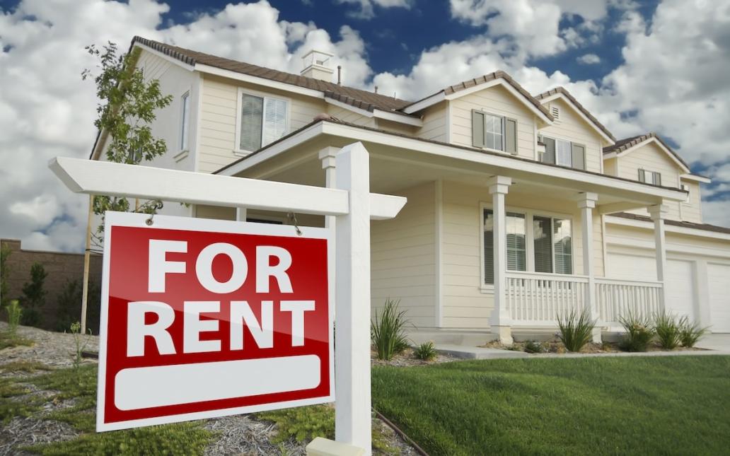 A single-family home that has a red "For Rent" sign in the front yard