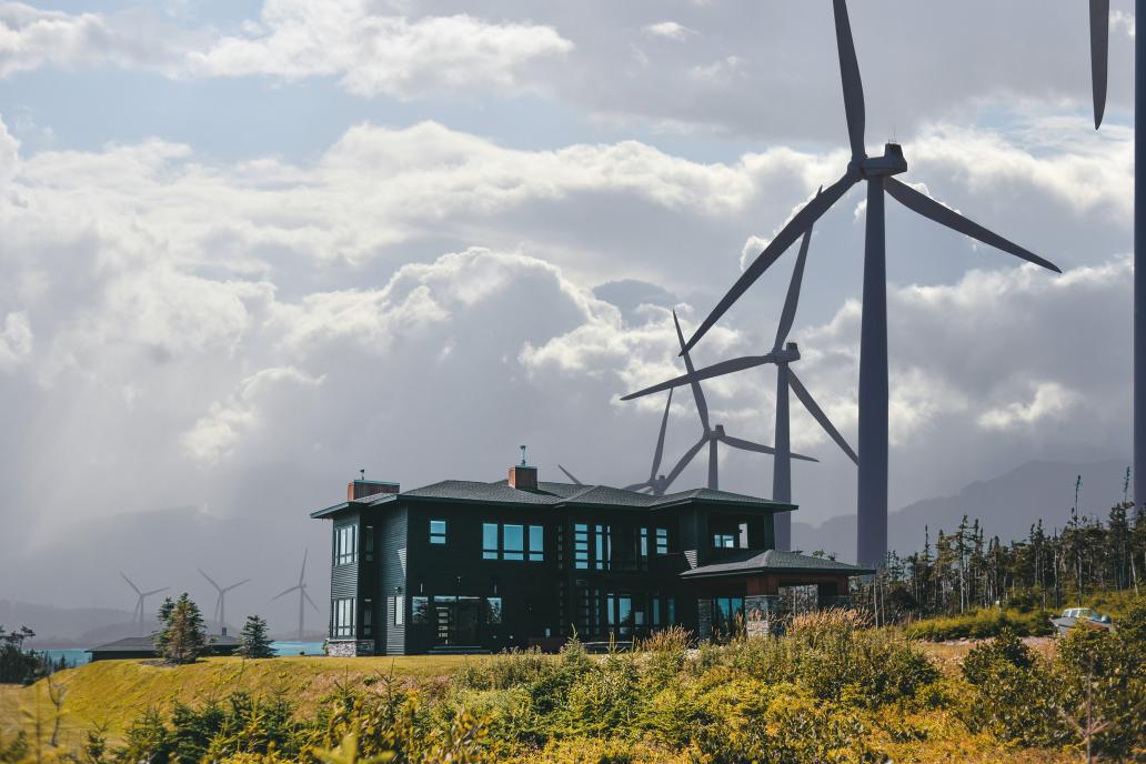 Modern farmhouse on hill with windmills in back