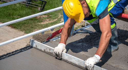 Construction worker leveling concrete on jobsite