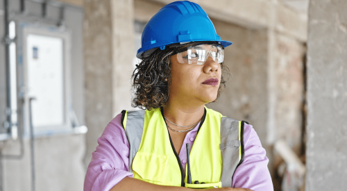 Woman in blue hard hat and yellow safety vest on construction jobsite