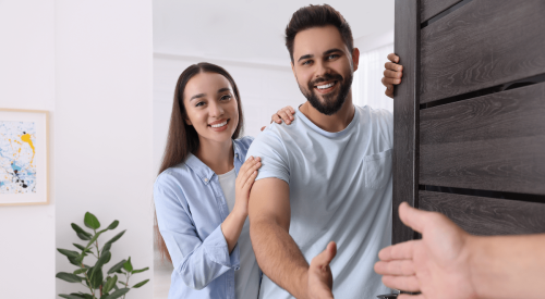 Young couple of renters welcoming as they open the door to their apartment