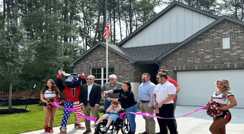 Ellenbeck family, along with homebuilding team, cutting a ribbon in front of newly built home