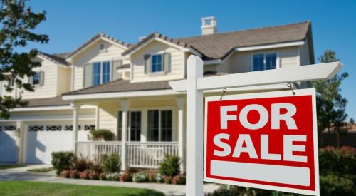 "For Sale" sign on front lawn of a single-family home