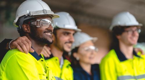 Profile view of four construction workers standing together and smiling