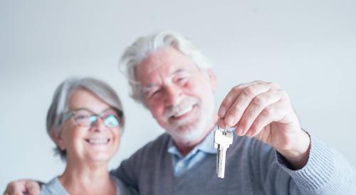 close up of mature man and woman holding a key of a new home