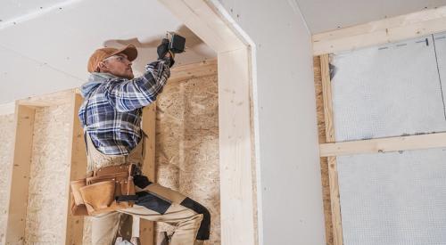 Worker on ladder works on dry wall