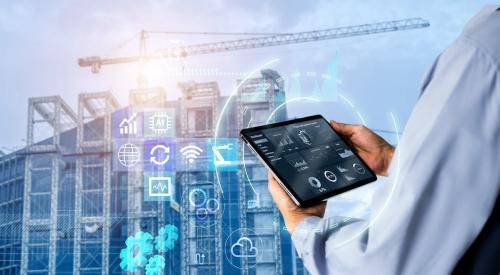 Construction worker at job site looking at tablet, icons floating in front of building that is under construction