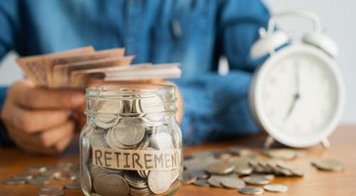 Gen Xer sits at table counting money, in front of them is a clock and a jar labelled "retirement" with coins spilling out