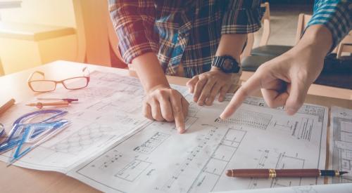 Two home builders look over plans on table