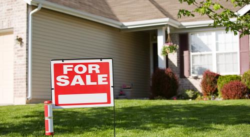 Red "For Sale" sign in front lawn of single-family home