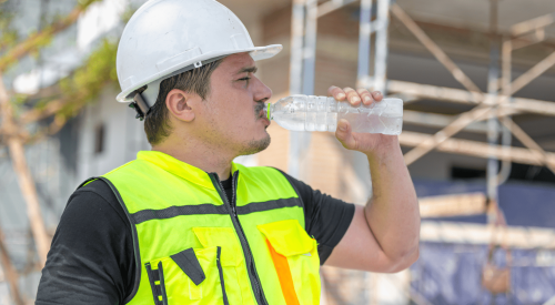 Construction worker drinking bottle of water during heat