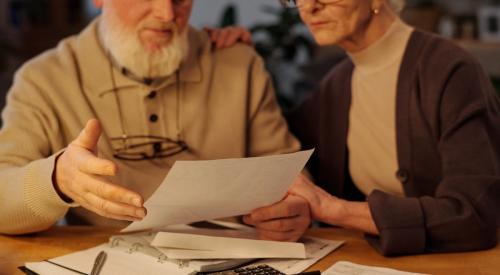 An older couple sits at a table, looking over budget