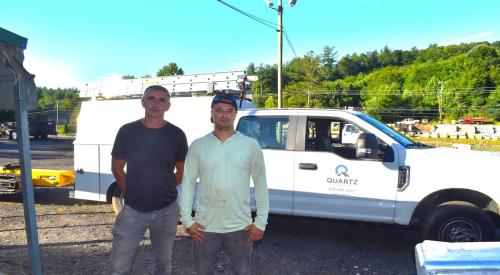 Ukrainian refugees stand in front of Quartz Properties Management work truck 