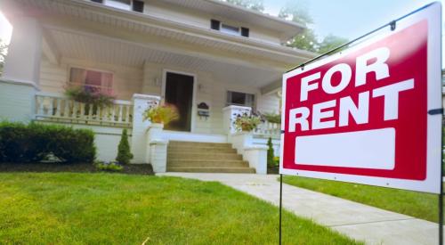 Red sign reading "For Rent" sits on front lawn of single-family home