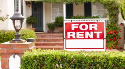 A red sign reading "For Rent" sits in front of a single-family house.