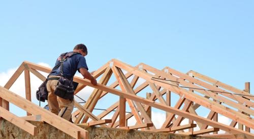 A builder works on the roof of a house.