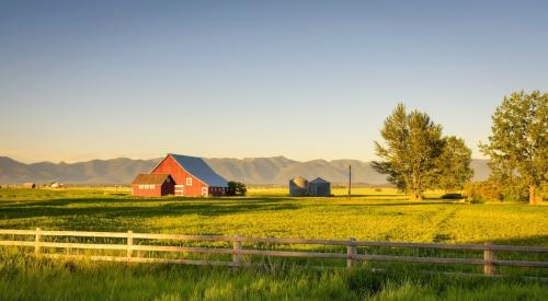 A red barn sits in the middle of an open field.