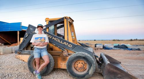 Lisa Morey, founder of Nova Terra, stands in front of machinery at a project site.