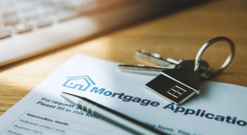 A mortgage application sits on a desk with a pen and a house key on top of it