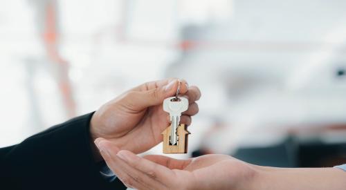 A real estate agent hands a key over to a homebuyer